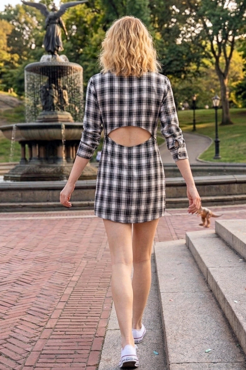 Woman walking in a park wearing a plaid dress with a cutout back.