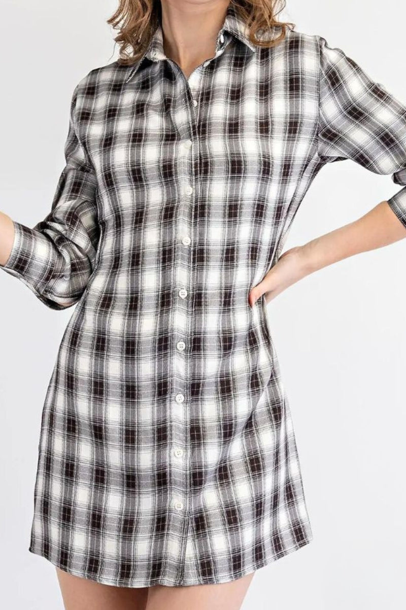 Person wearing a black and white plaid shirt dress on a plain background