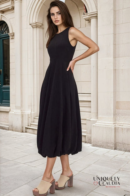 Woman wearing a black dress standing in front of a building with columns.