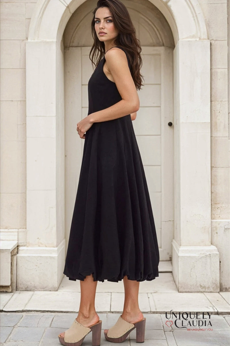 Woman wearing a black dress standing in front of a stone archway.