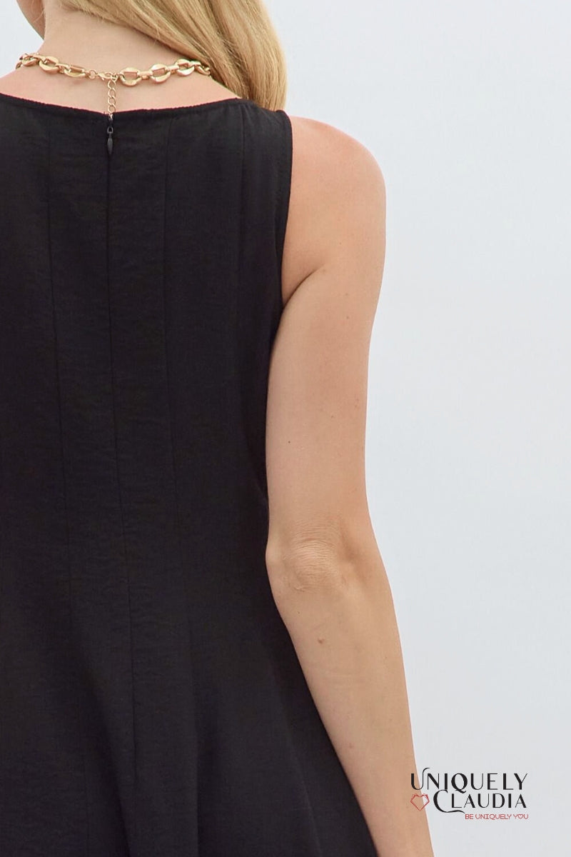 Black sleeveless dress worn by a person with a gold necklace on a white background, featuring the brand 'Uniquely Claudia'.
