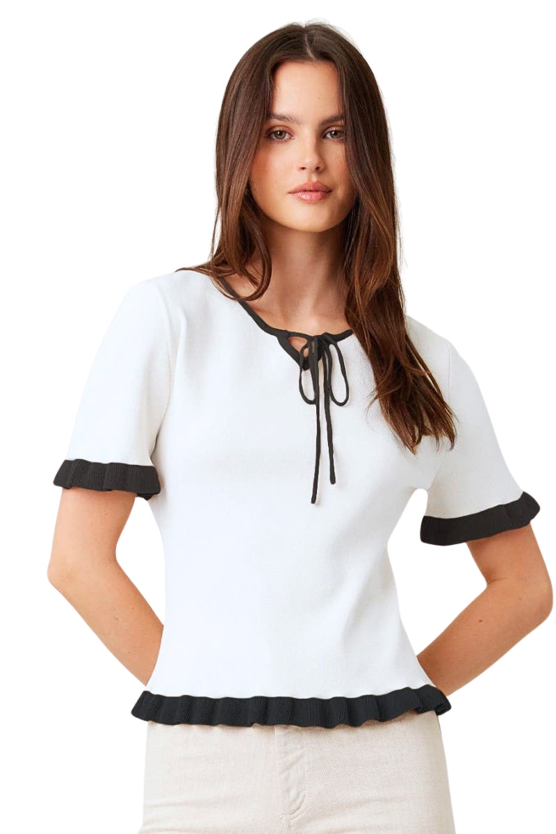 Woman wearing a white blouse with black trim on a white background