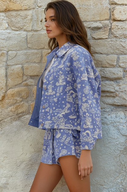 Woman wearing a blue patterned outfit standing against a stone wall.