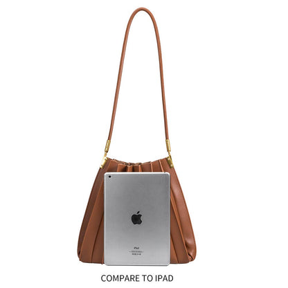 Brown handbag with an iPad for size comparison on a white background