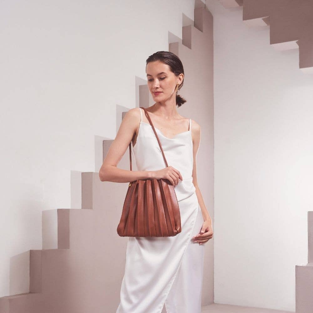 Woman holding a brown leather handbag in a minimalistic setting