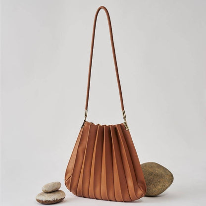 Brown pleated handbag with a strap on a light gray background