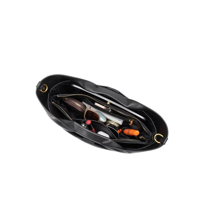 Black leather bag with various items inside on a white background