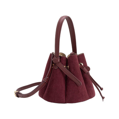 Maroon handbag with brown leather straps on a white background