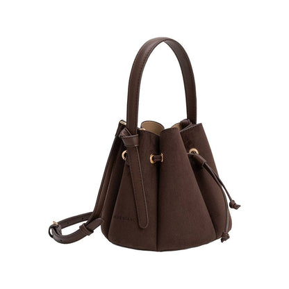 A dark brown bucket bag with a top handle and shoulder strap, featuring gold-tone hardware and drawstring details, shown against a plain white background.