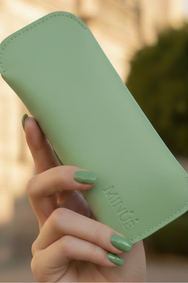 Hand holding a green phone case with 'MINUE' branding outdoors.