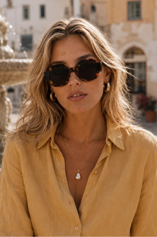 Woman wearing sunglasses and a yellow shirt in an outdoor setting
