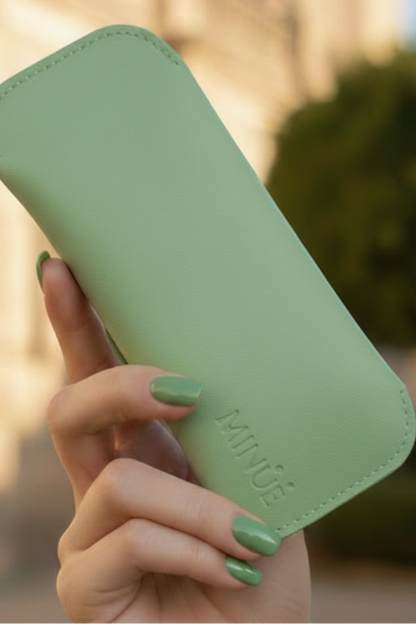 Hand holding a green phone case with MINUE branding outdoors.