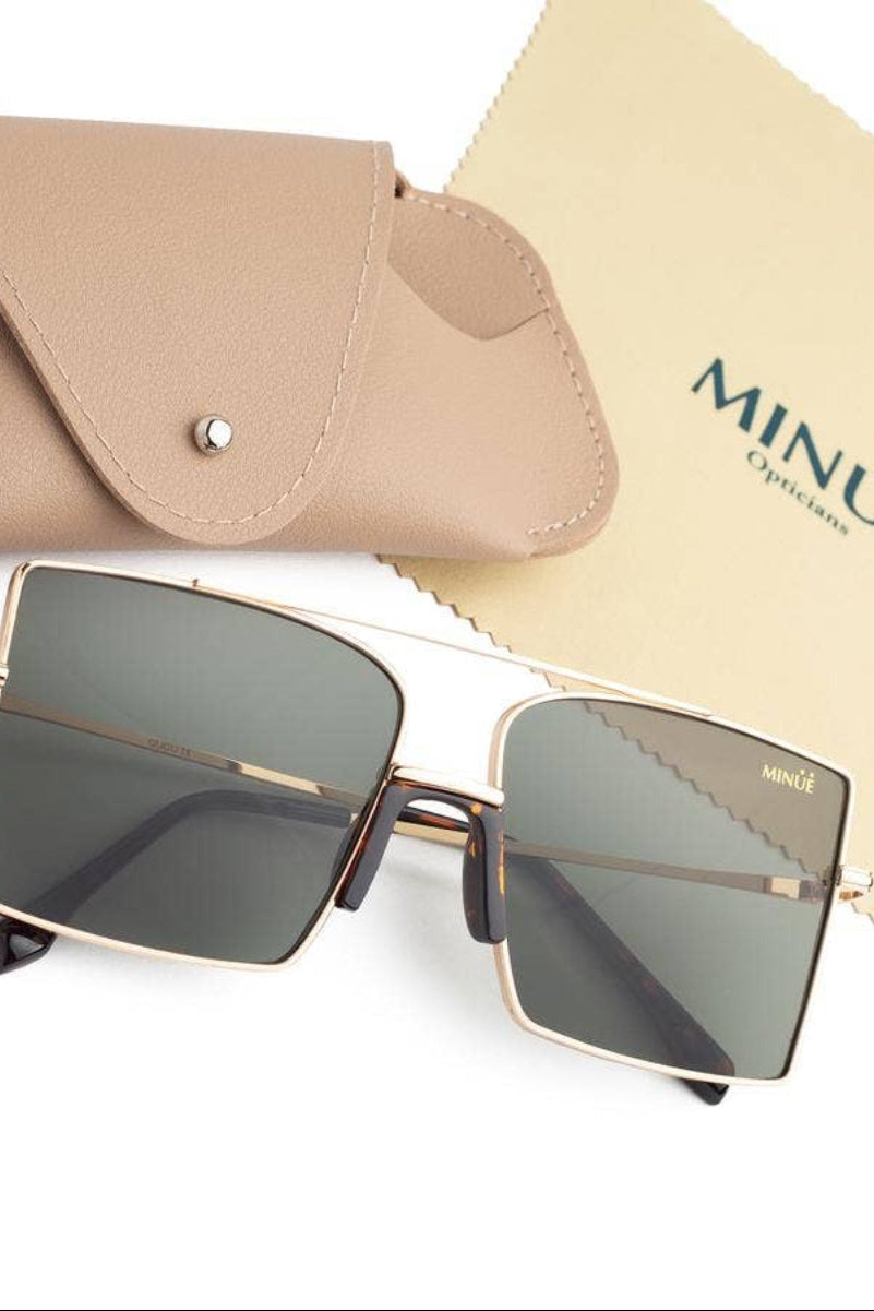 Square metal-frame sunglasses with dark tinted lenses, shown with a beige leather case and a branded MINÚE Opticians cloth on a white background.