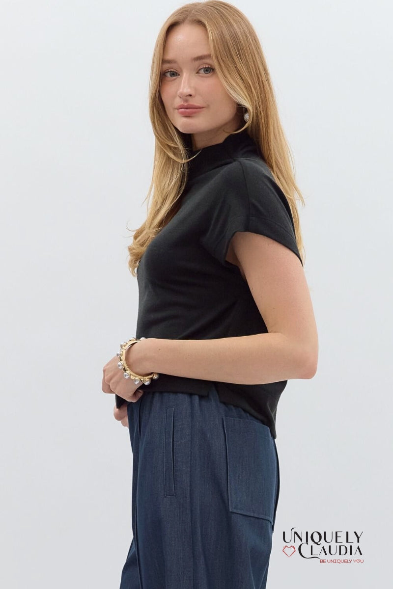 Woman wearing a black sleeveless top and blue pants on a white background with 'Uniquely Claudia' branding.