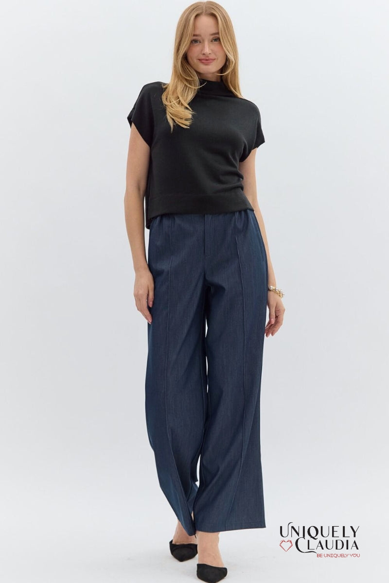 Woman wearing a black top and navy pants on a white background with 'Uniquely Claudia' branding.