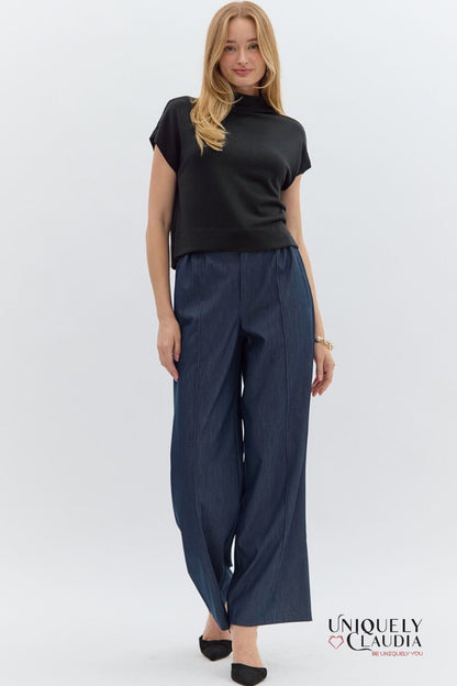 Woman wearing a black top and navy pants on a white background with 'Uniquely Claudia' branding.