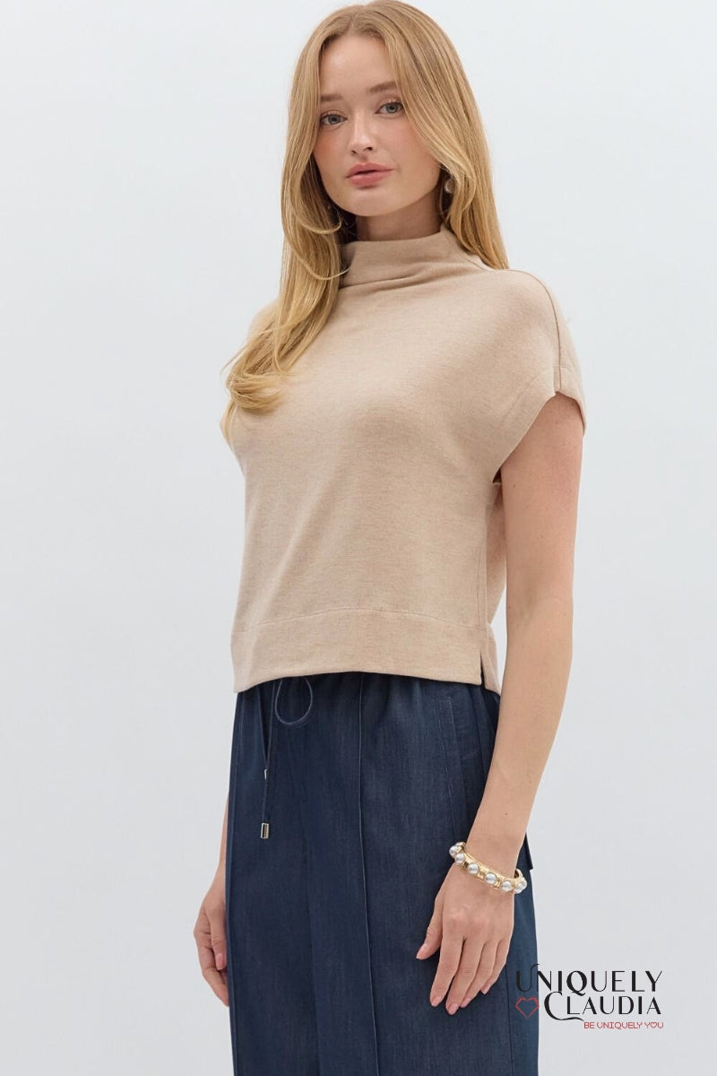 Woman wearing a beige sleeveless top and navy pants on a white background with 'Uniquely Claudia' branding.