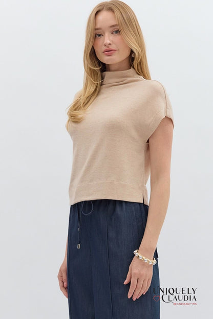 Woman wearing a beige sleeveless top and navy pants on a white background with 'Uniquely Claudia' branding.