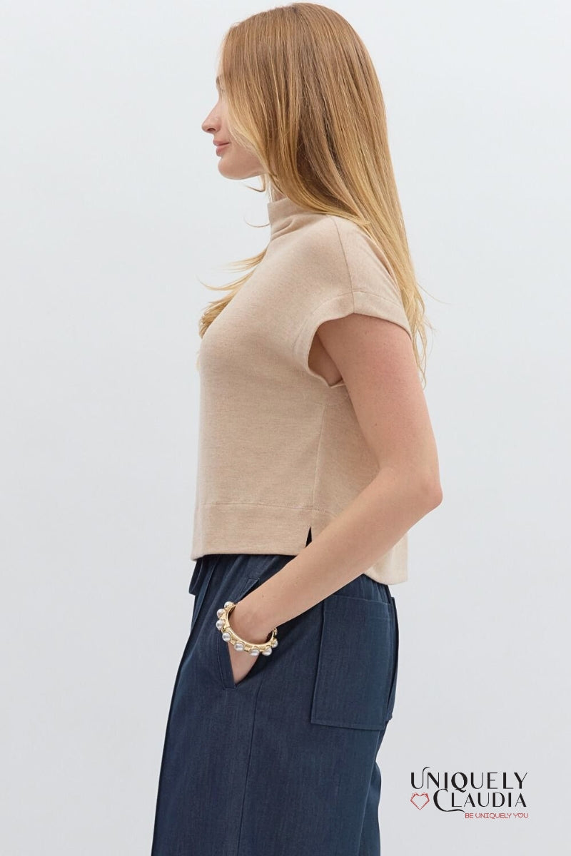 Woman wearing a beige top and navy pants with a white background, featuring the brand 'Uniquely Claudia'.