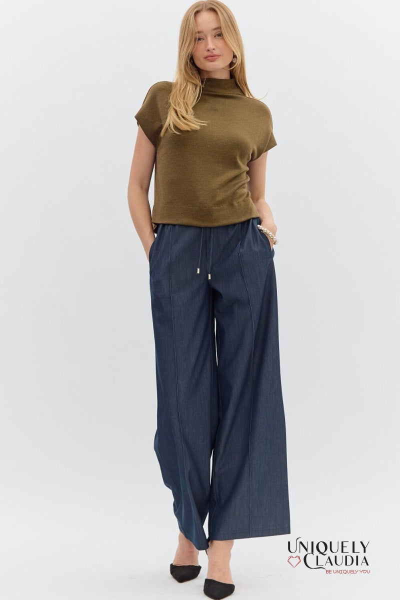 Woman wearing a green top and navy wide-leg pants on a white background