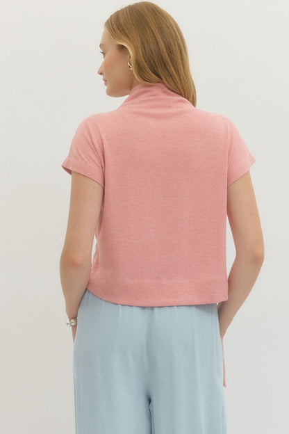 Person wearing a pink top and light blue pants on a plain background