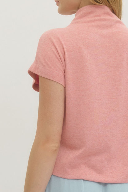 Person wearing a pink short-sleeve top against a white background