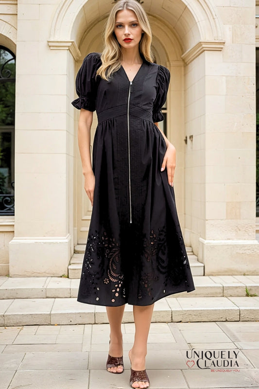 Woman wearing a black dress with puffed sleeves in front of a classical building.