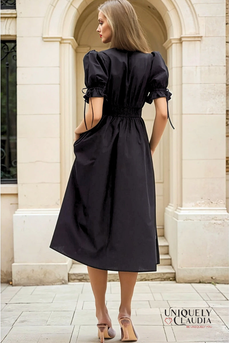 Woman wearing a black dress standing in front of a stone building
