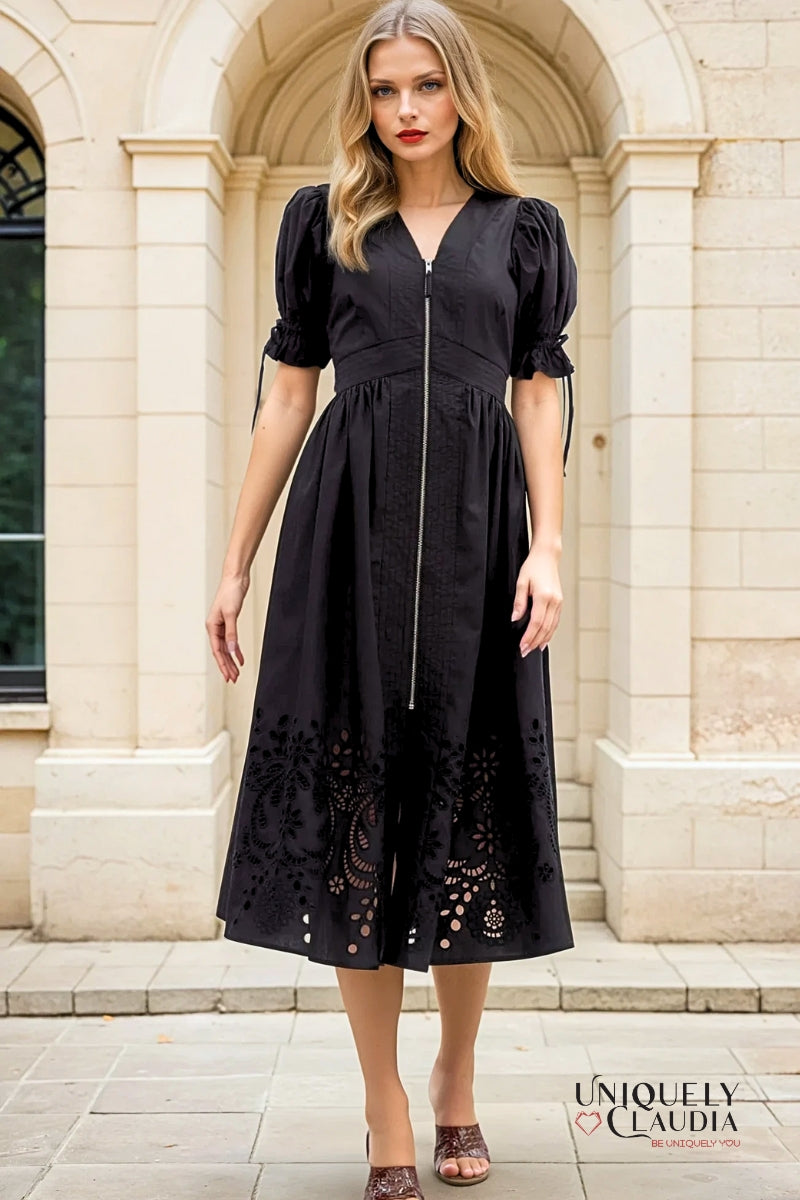 Woman wearing a black dress with puff sleeves and lace details in front of a stone building.