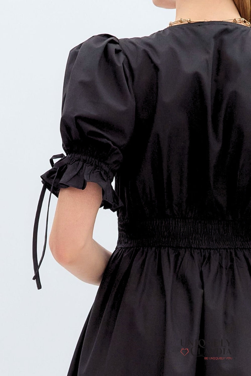 Black dress with puffed sleeves on a plain background