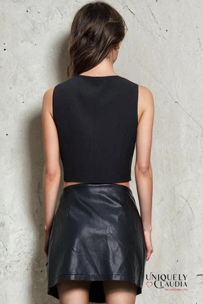 Woman wearing a black sleeveless top and leather skirt against a textured wall, with 'Uniquely Claudia' branding.