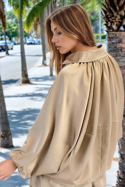 Woman wearing a beige blouse with a street and palm trees in the background