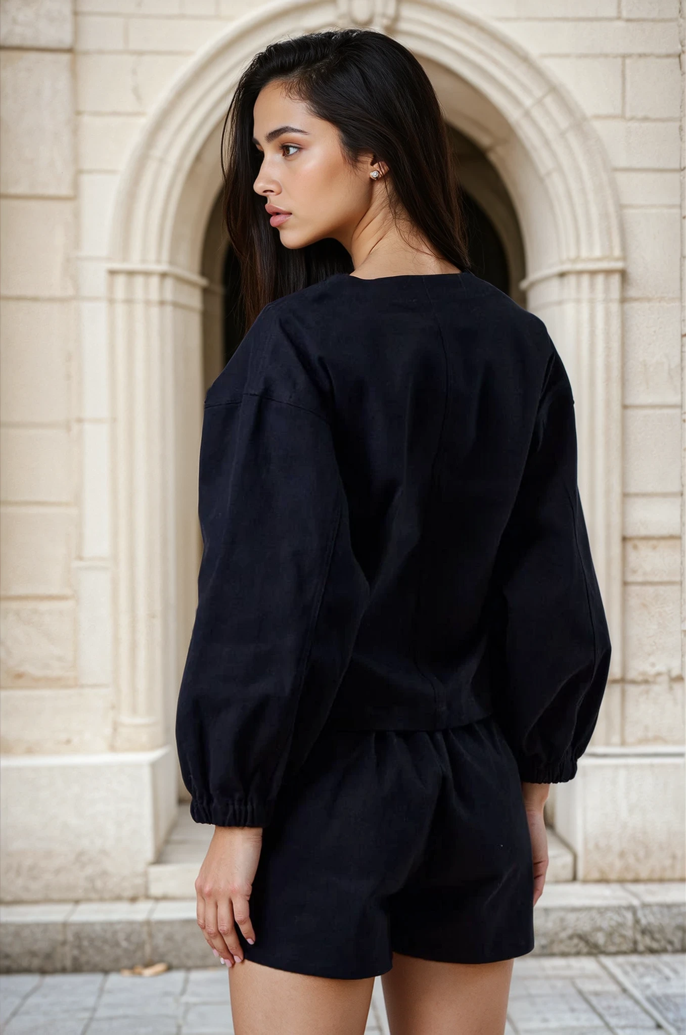 Woman wearing a black outfit standing in front of an archway.