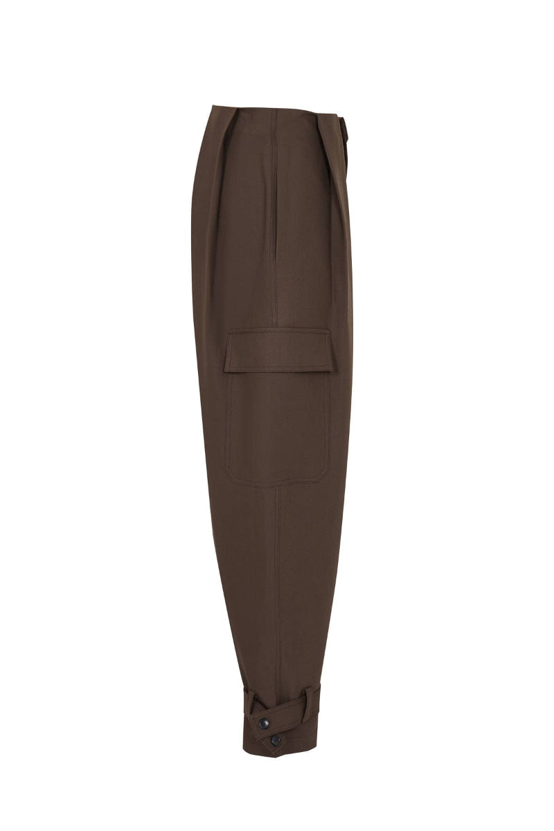 A pair of dark brown cropped trousers with a unique tapered silhouette, featuring a flap pocket on the upper thigh and buttoned cuffs at the hem, shown against a plain white background.