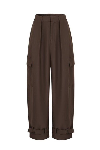 A pair of high-waisted, wide-leg cargo pants in a dark brown color, featuring pleated detailing at the waist, side cargo pockets, and ruffled cuffs at the hem, shown against a plain white background.