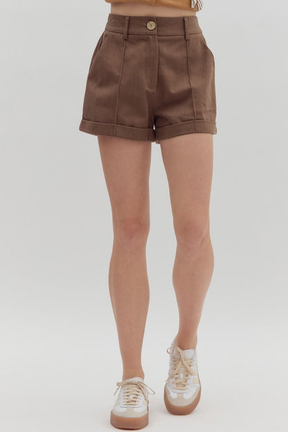 Brown shorts worn by a person on a white background