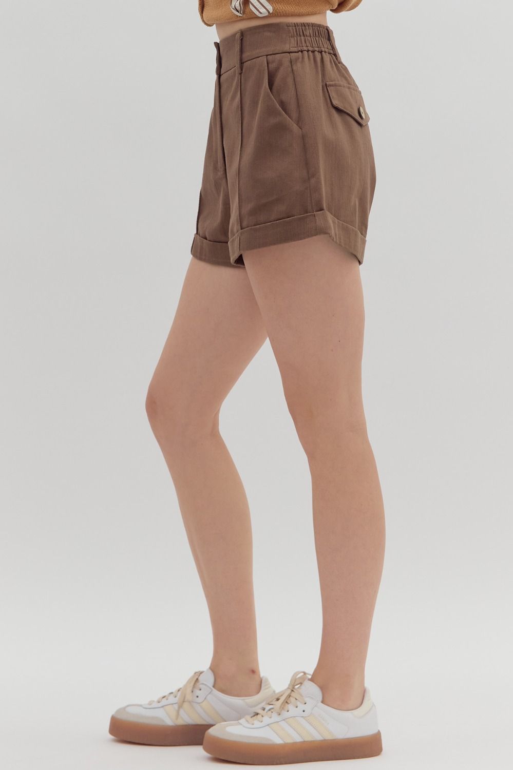 Brown shorts worn by a person on a white background