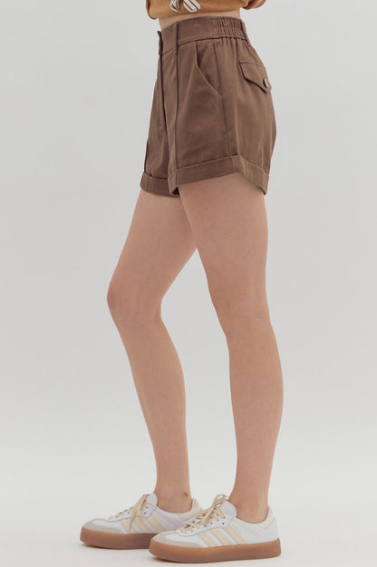Brown shorts worn by a person on a white background