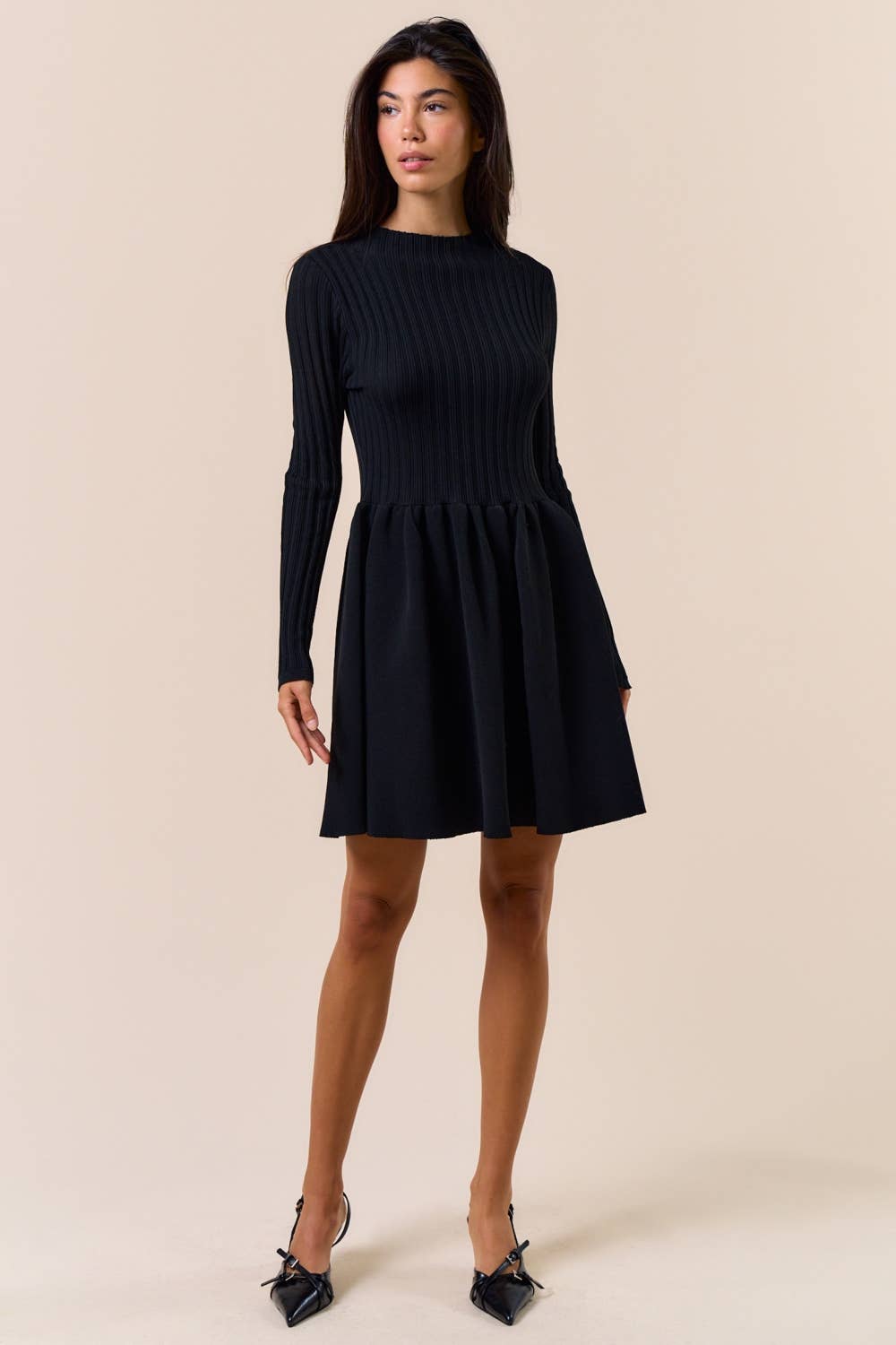 Woman wearing a black dress against a beige background