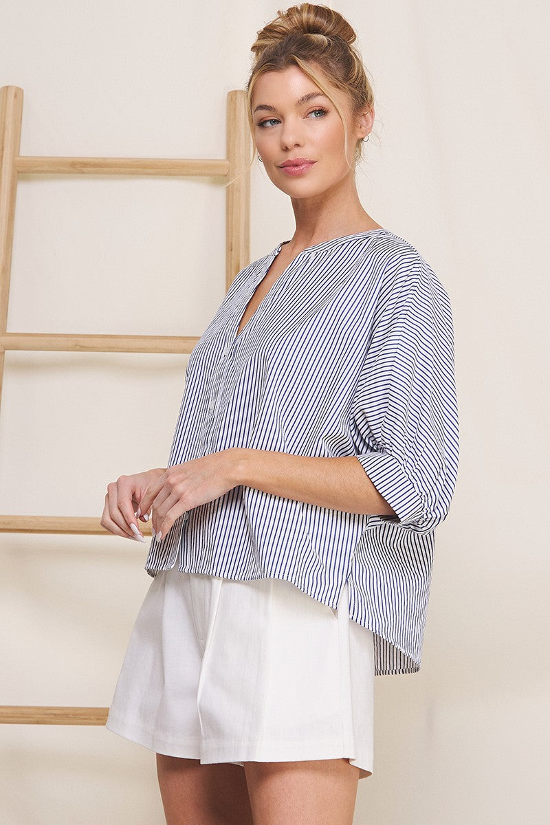 Woman wearing a blue and white striped top over a white dress against a light background