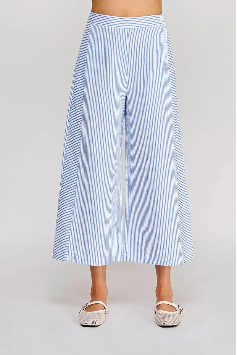 Blue and white striped wide-leg pants worn by a person on a light gray background
