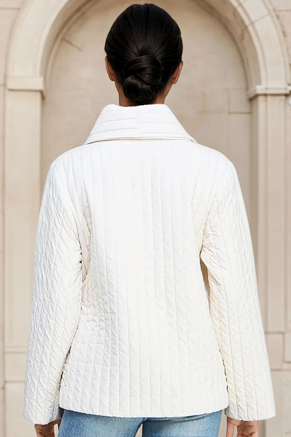 Person wearing a white quilted jacket with a neutral background