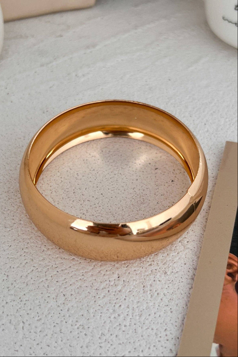 Gold bangle on a textured surface