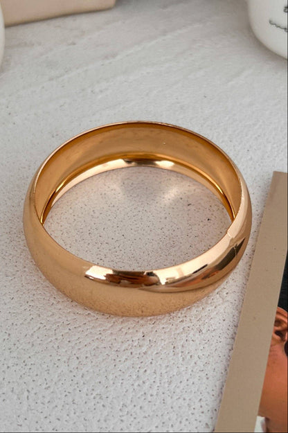 Gold bangle on a textured surface