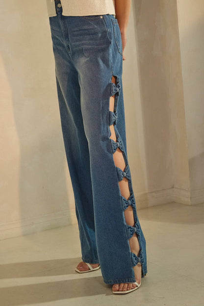 Blue jeans with cut-out side panels worn by a person on a neutral background