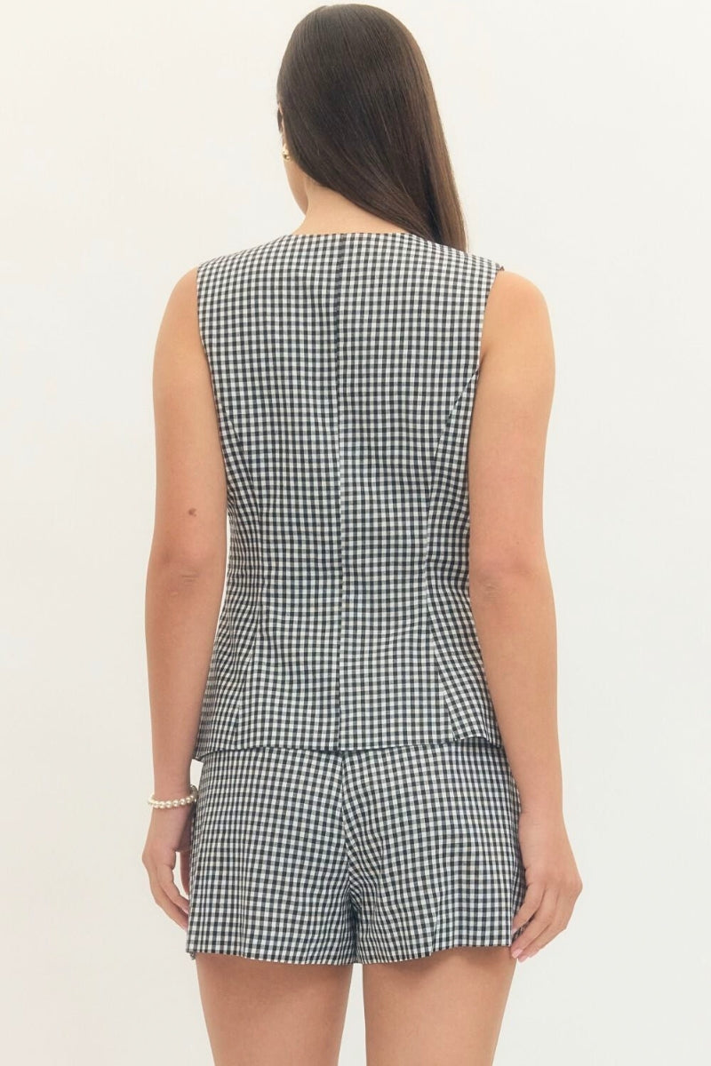 Person wearing a black and white checkered romper on a plain background