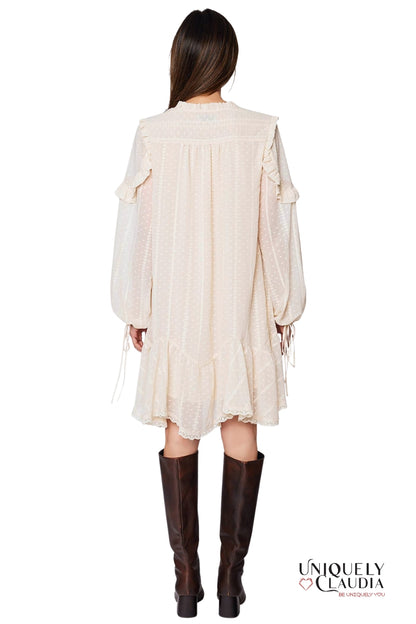 Woman wearing a cream-colored dress with long sleeves and brown knee-high boots on a white background.