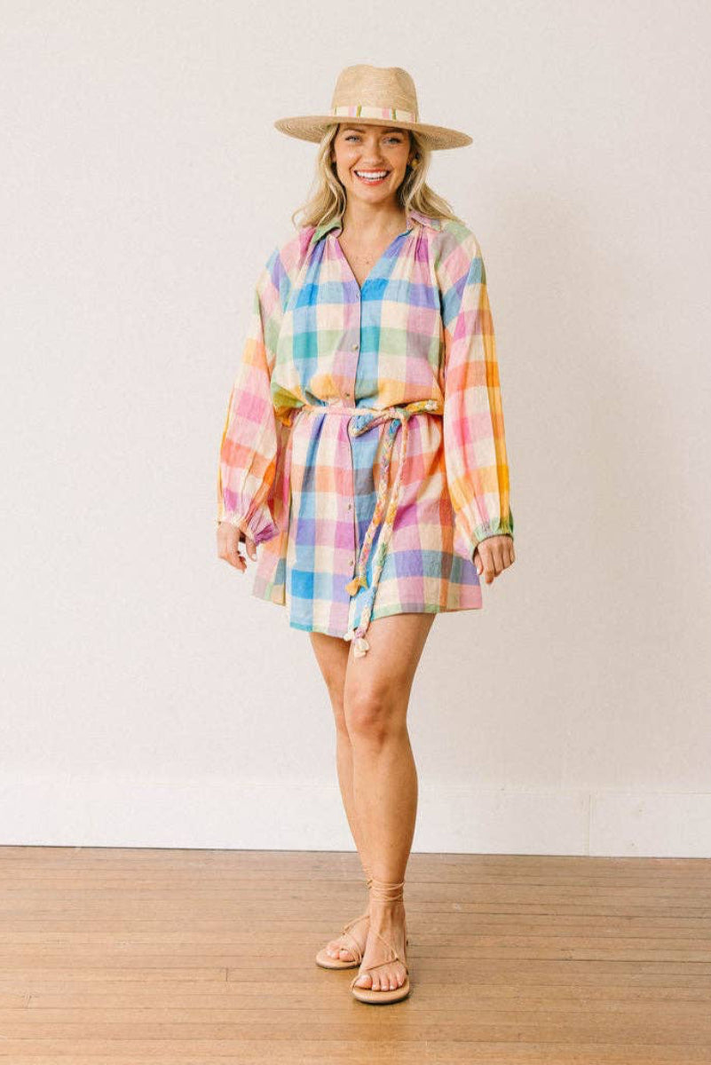 Woman wearing a colorful plaid dress and hat on a plain background