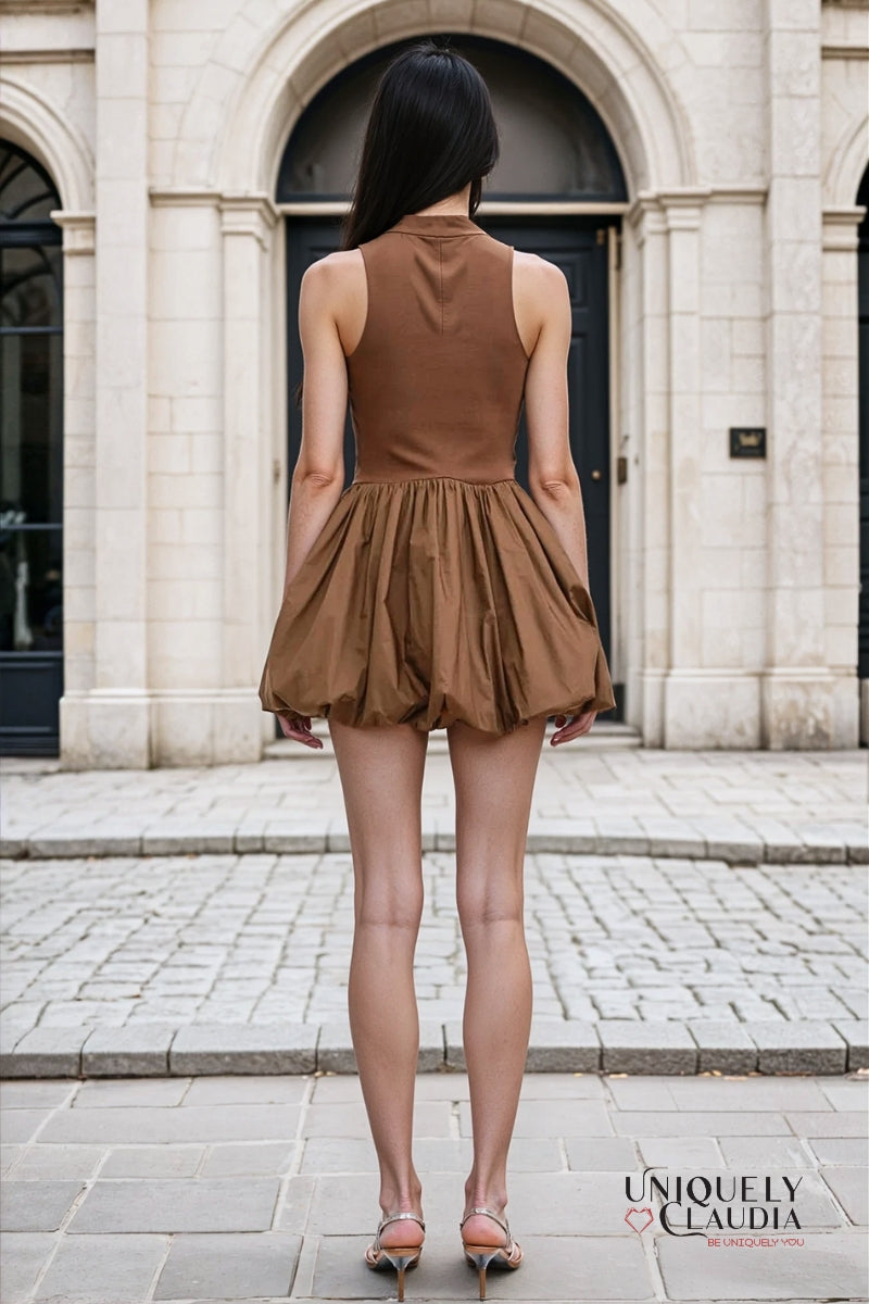 Woman wearing a brown bubble dress standing in front of a stone building