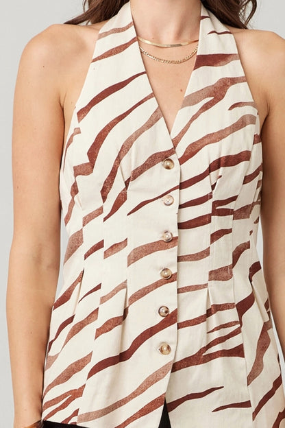 Woman wearing a sleeveless vest with zebra pattern and gold buttons on a plain background